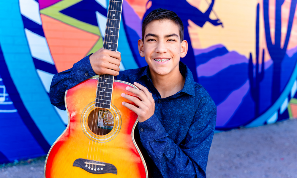 Young student taking guitar lesson in Tucson at Allegro School of Music and Dance with supportive teacher.